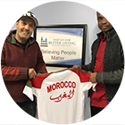 Hassan DaFrane and Andrew Thomas, Jr. holding a Moroccan national soccer jersey with Morocco written in English and Arabic on it.
