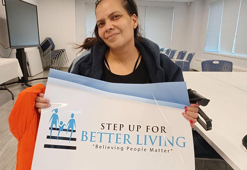 Client YS holding a Step Up for Better Living sign.